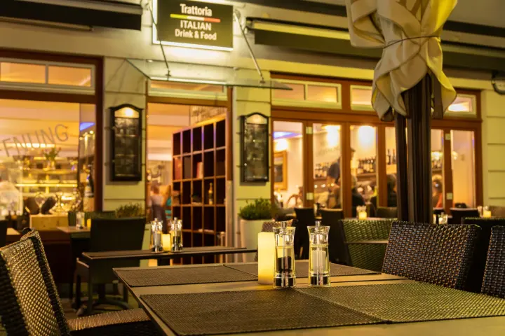 Terrasse vor dem beleuchteten Eingang der Trattoria